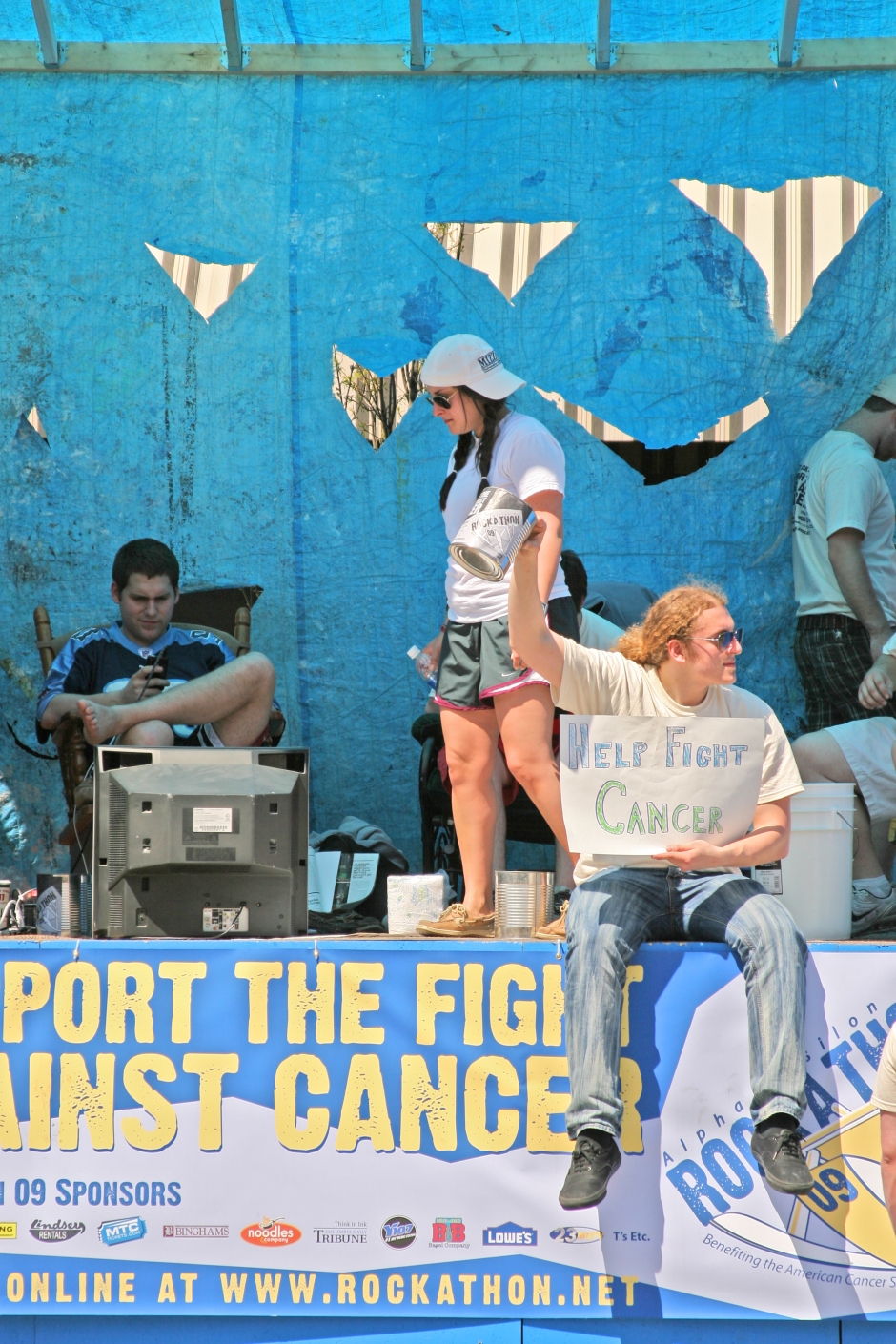 Alpha Epsilon Pi member Matt Fleischer, senior, left, sits back in his rocking chair as Zach Denison, senior, right, raises a can for donations during the 2009 Rock-A-Thon Thursday afternoon in downtown Columbia. As apart of the largest single fraternity philanthropy, Fleischer must sit in a rocking chair for 63 consecutive hours while fraternity members solicit support and donations in an effort to help aid cancer research.